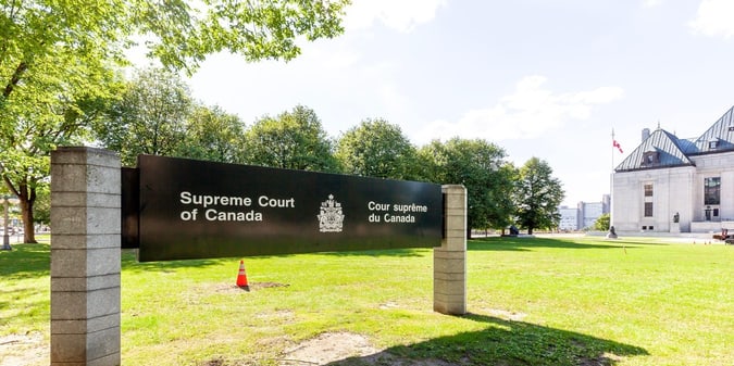Supreme Court of Canada bilingual entrance sign on the grounds of the courthouse in Ottawa, with the Canadian flag visible in the background. Supreme Court of Canada bilingual entrance sign on the grounds of the courthouse in Ottawa, with the Canadian flag visible in the background.