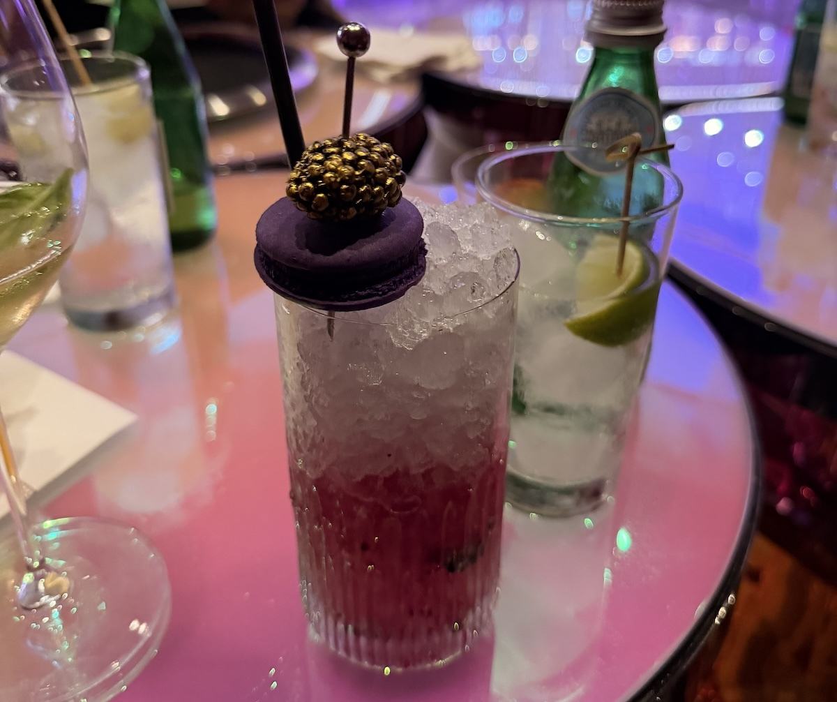 The First Spritz cocktail topped with a cassis macaron and gold-dusted blackberry at Chandelier Bar