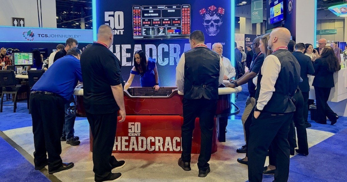 Casino executives and attendees gather around the 50 Cent Headcrack table during a demo at the Global Gaming Expo