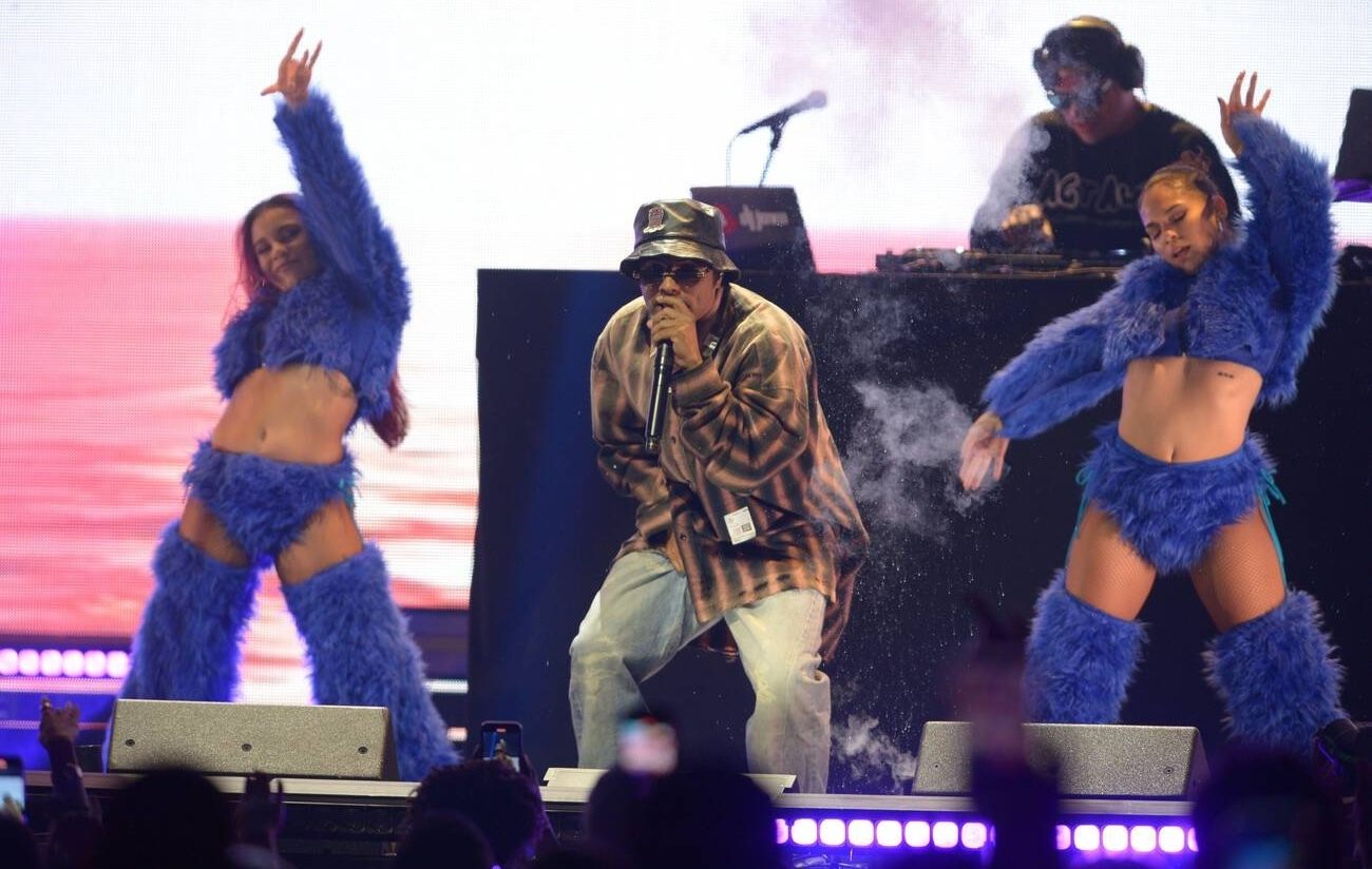 Chencho Corleone performing on stage with two dancers