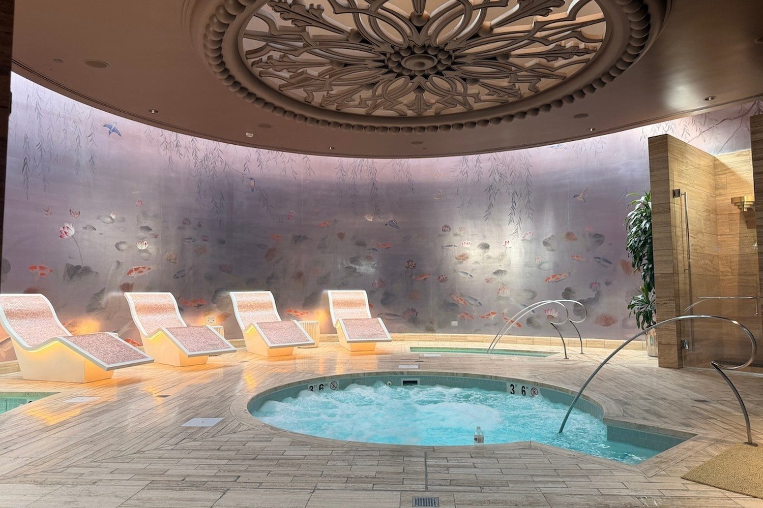 Jacuzzi and heated tepidarium chairs in front of a painted mural at the Wynn Spa