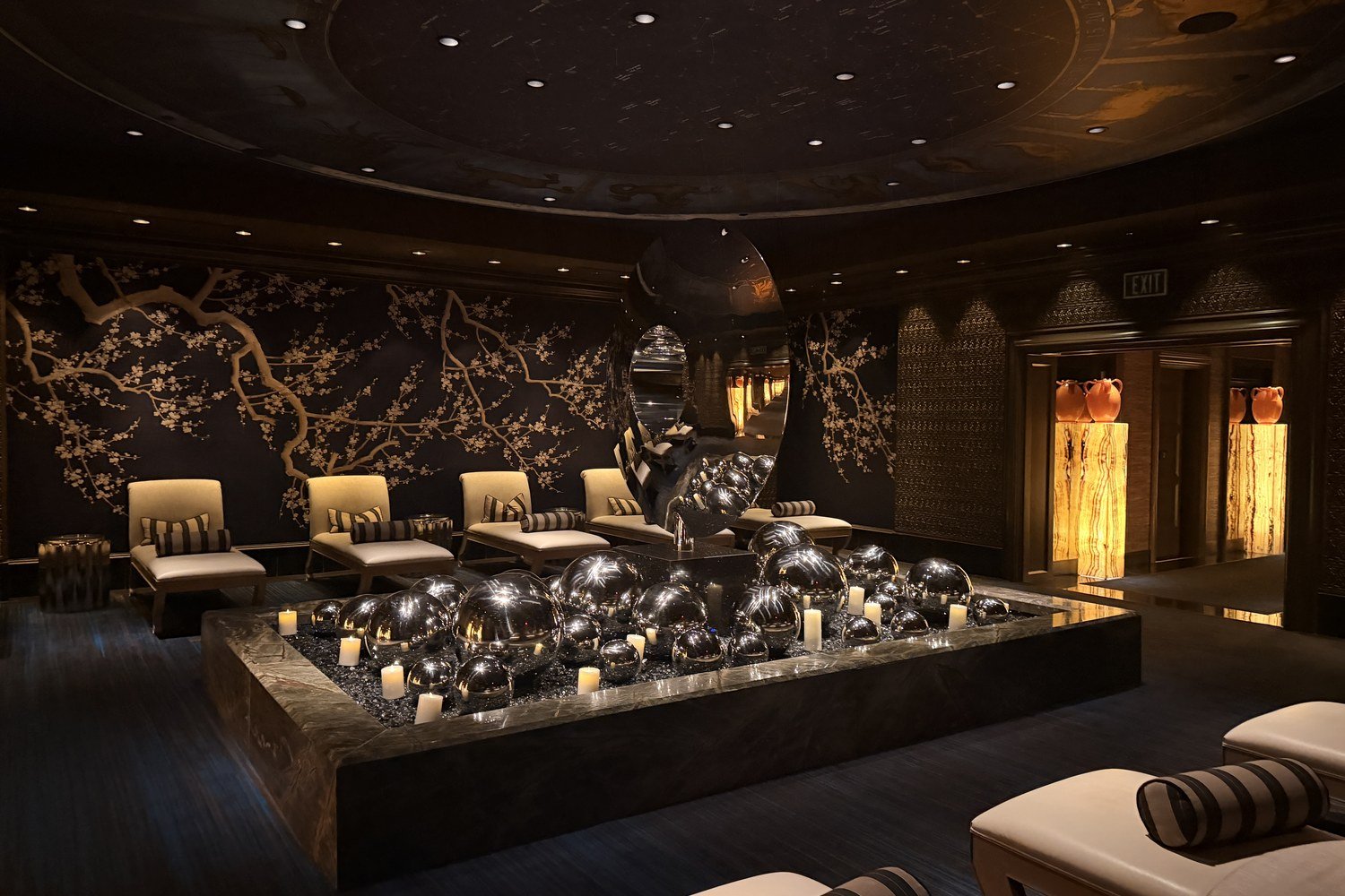 Zodiac lounge at the Wynn Spa with a celestial ceiling, mirrored spheres and candles, and lounge chairs in front of a cherry blossom mural
