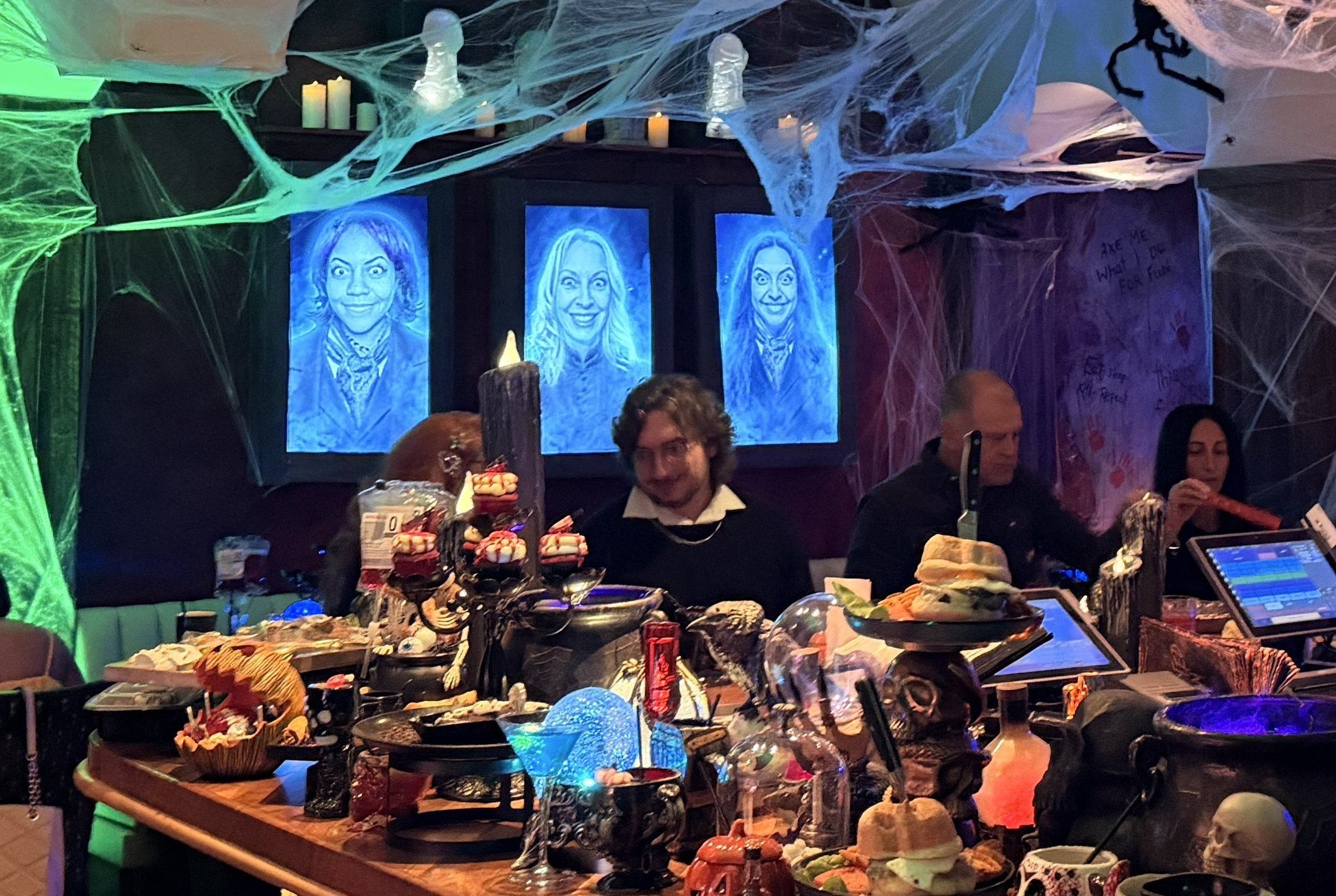 Glowing ghost portraits hang above the bar at Palms' Haunted Inn Halloween pop-up