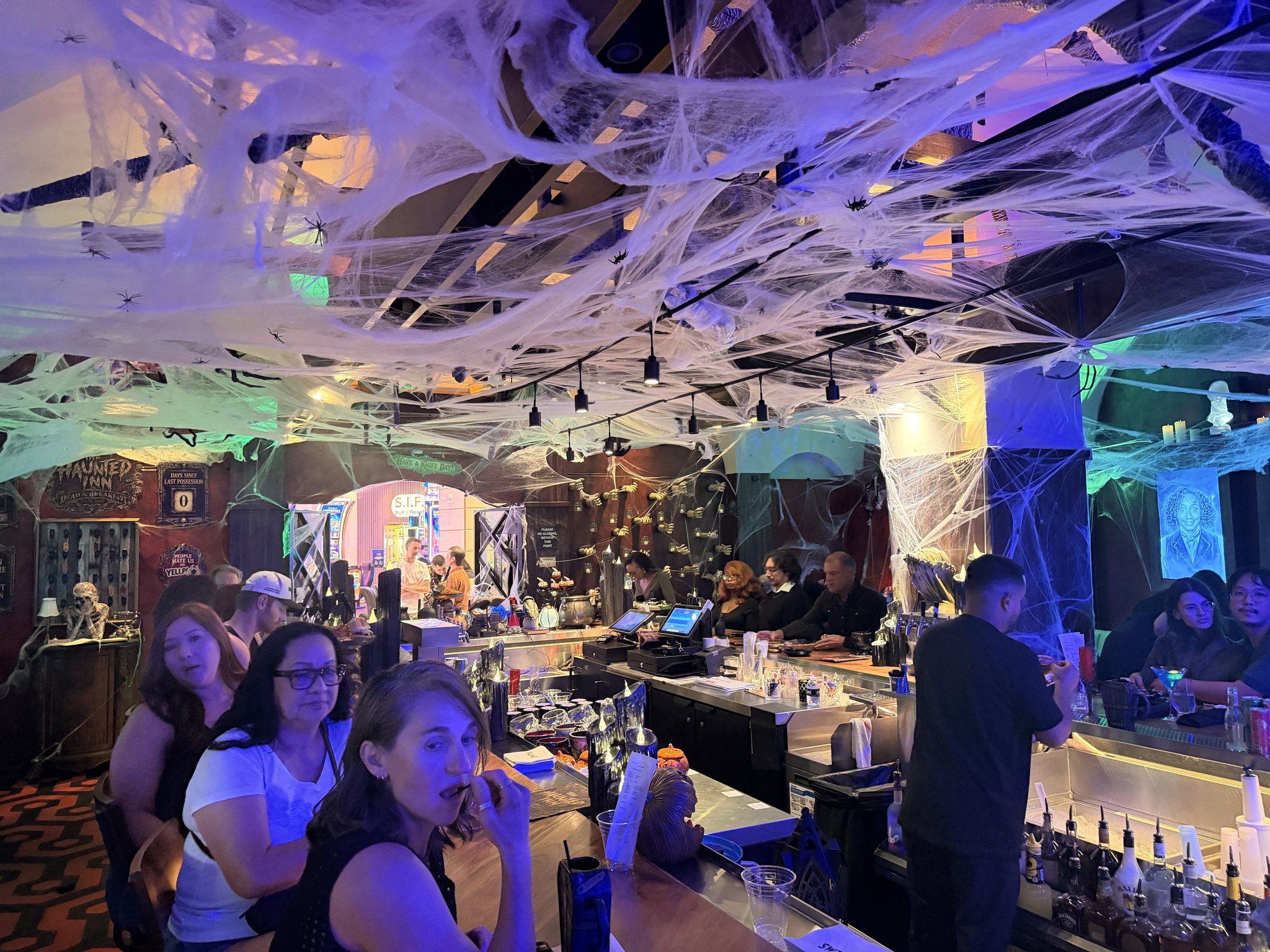 Cobwebs strung across the ceiling above the crowded bar at Palms' Haunted Inn Halloween pop-up