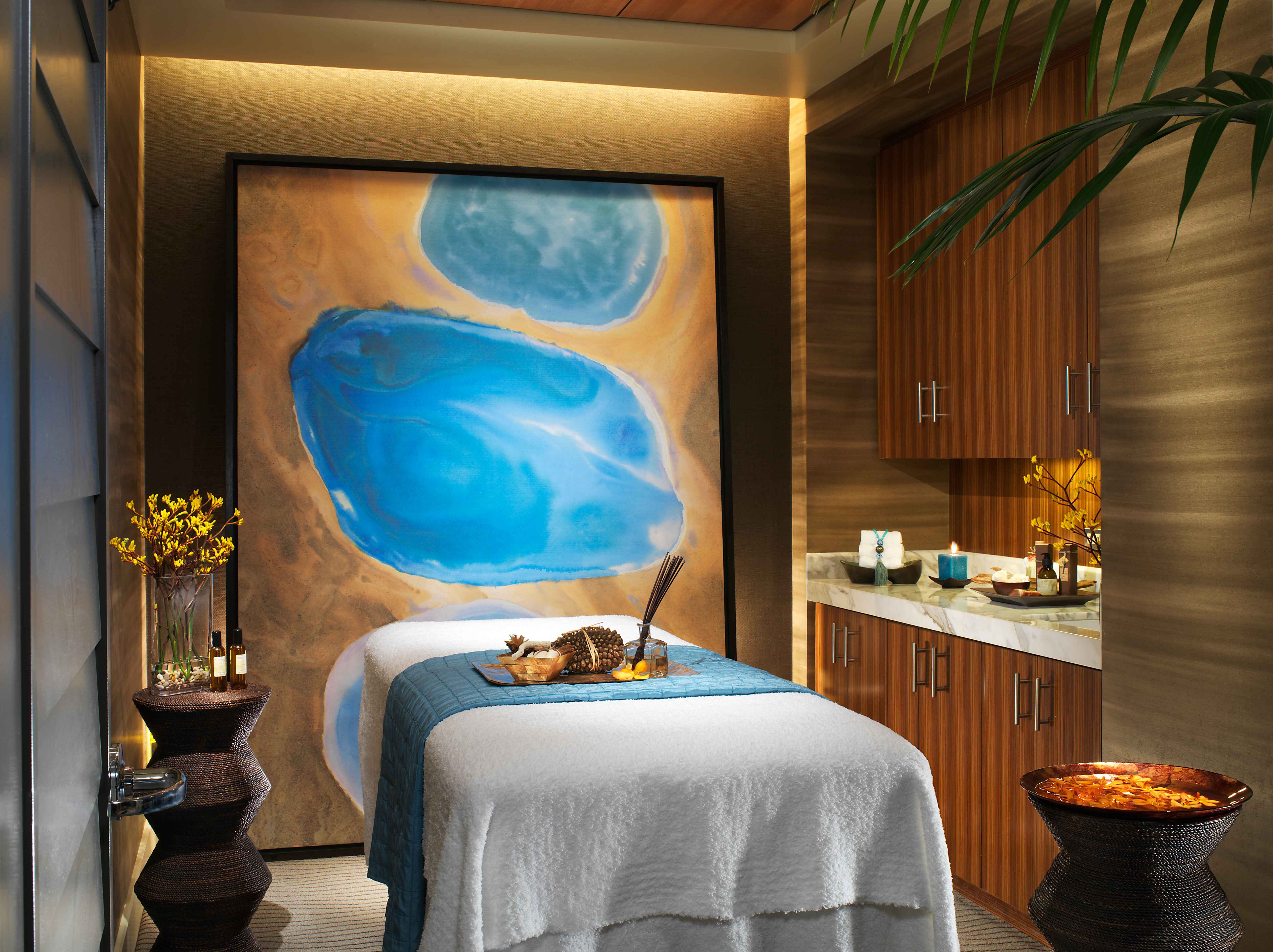 A treatment room for massages and other services at the spa inside Caesars Palace with a blue and yellow background and a massage bed that has pinecones and other materials on it.