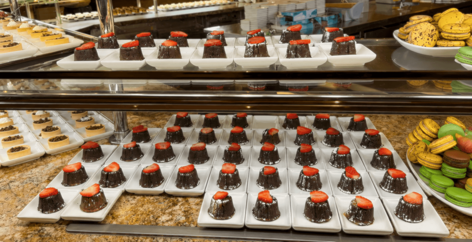 Several mini chocolate cakes and macarons in the dessert section of Bellagio Buffet.