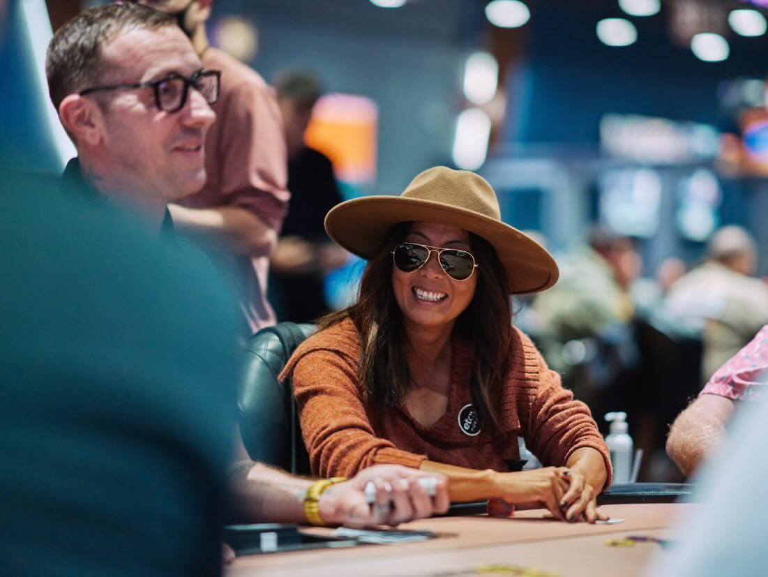 Esther Taylor sits at a poker table with a man to her left.