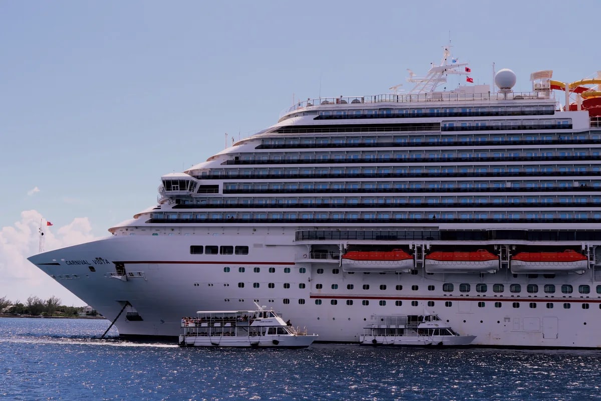 Carnival Vista cruise ship lit up at dusk near the coastline