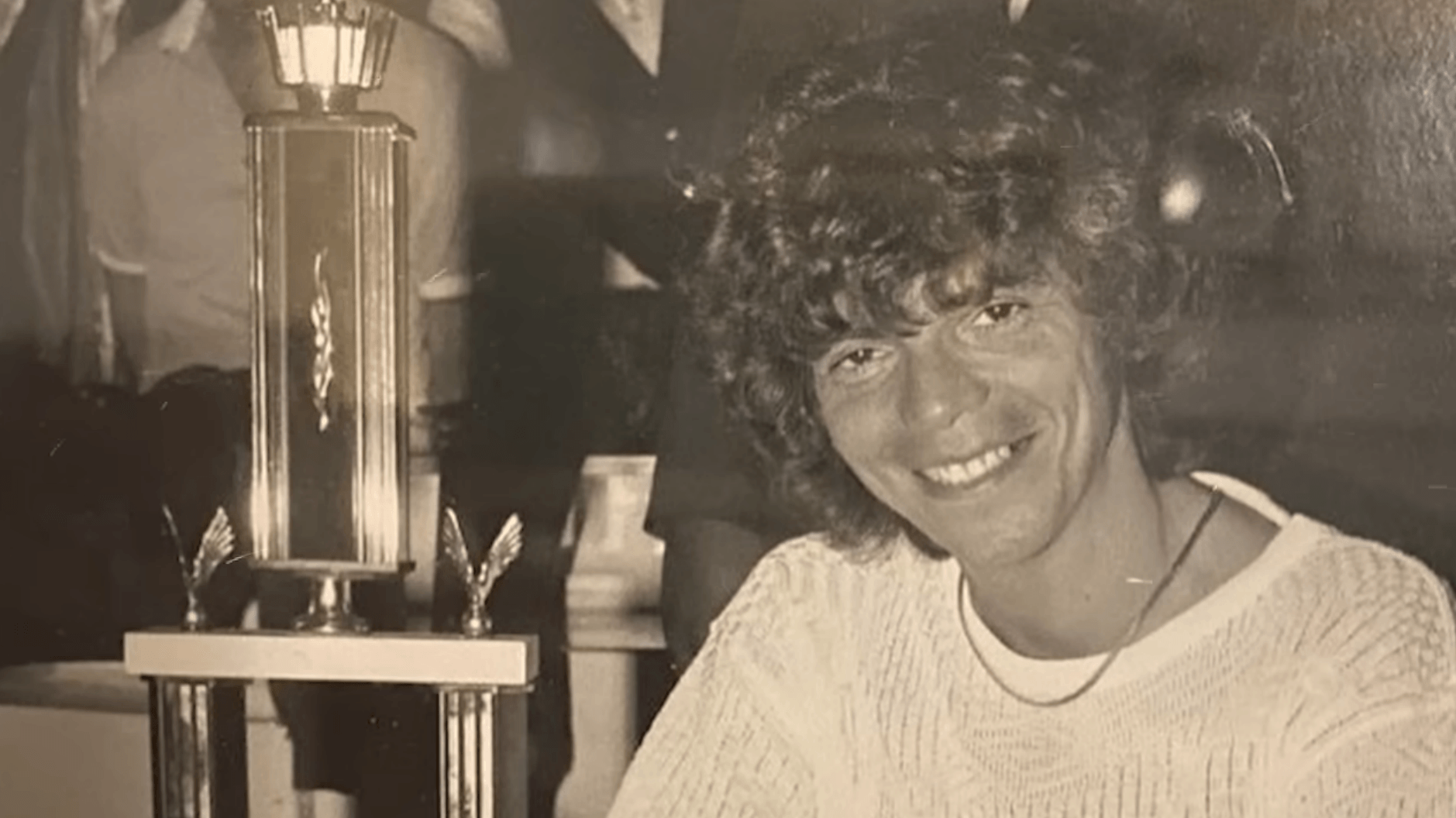 Stu Ungar, 3-time WSOP Main Event winner next to a trophy, black and white photo.