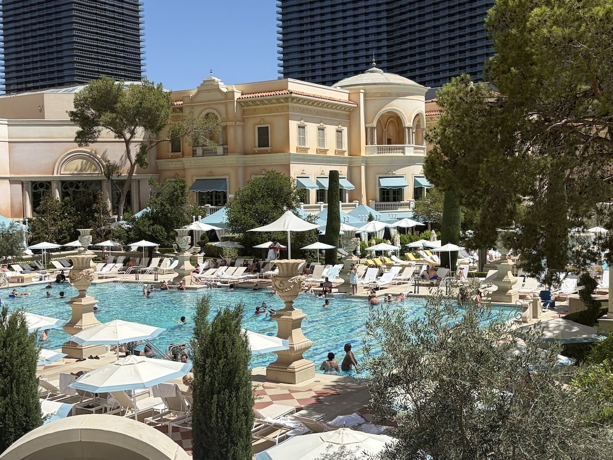 Bellagio's pool courtyard with palm trees, lounge chairs, umbrellas, and swimming pools viewed from Café Gelato.