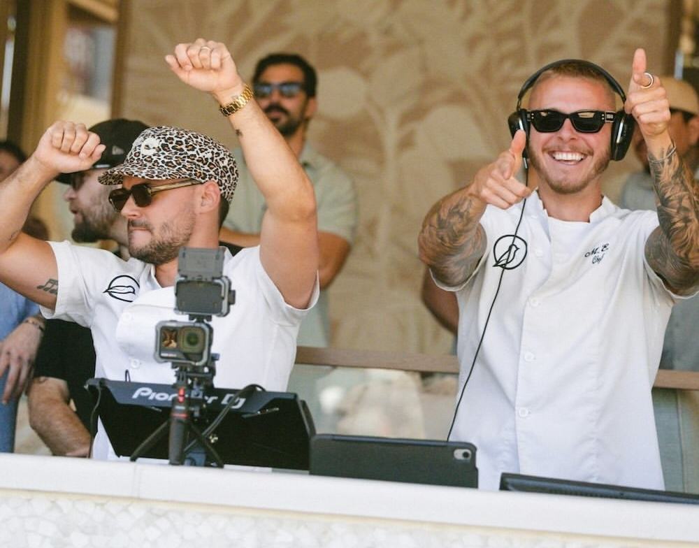 2 male DJs from Morning Wood kitchen during an omnia sober wellness event, dancing with sunglasses and chef shirts on