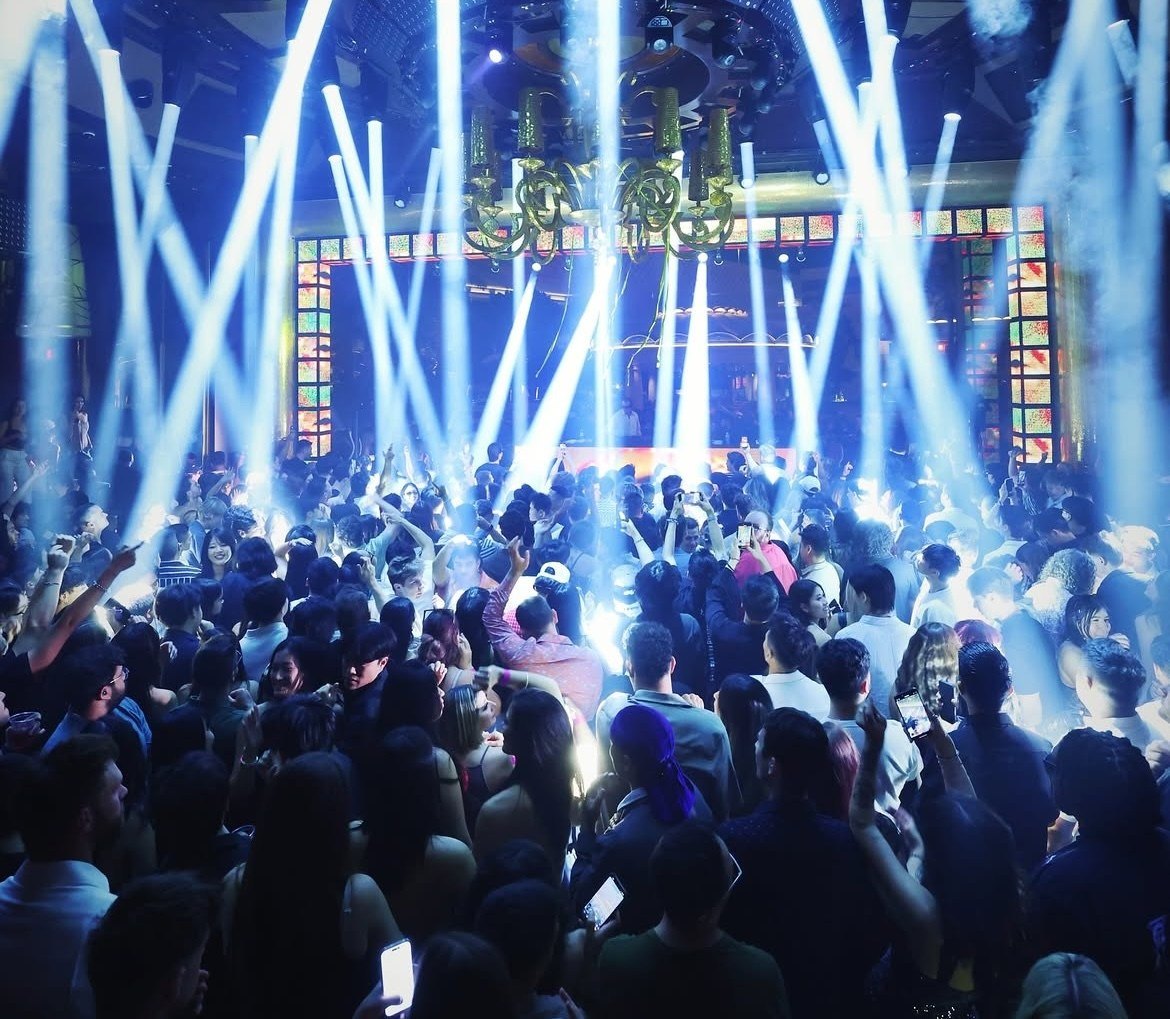 the main indoor area of XS nightclub at the Wynn, with many light beams shining down on the crowd and looking towards the stage. A large crowd is pictured.