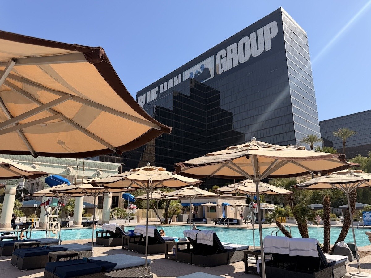 Umbrellas and daybeds along Luxor's North Pool deck, framed by the resort's tower displaying Blue Man Group signage