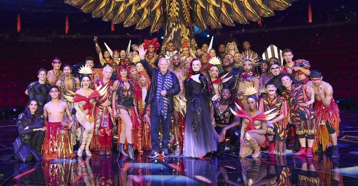 Several Awakening cast members stand with narrator Sir Anthony Hopkins, performers have outfits and surround him.