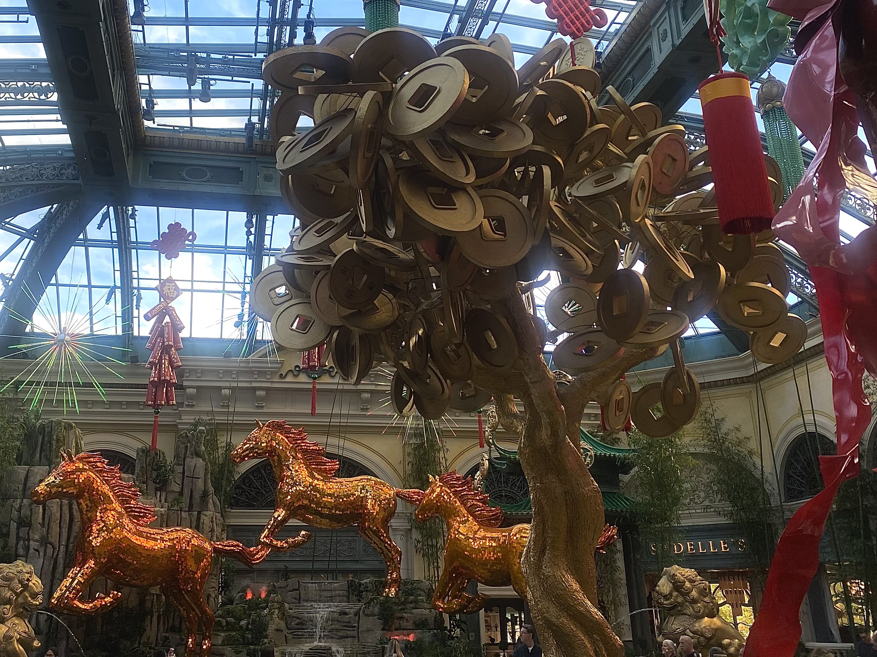 Gold coins in money tree in the Bellagio Conservatory's East bed, with three golden horses from the West Bed pictured in the background