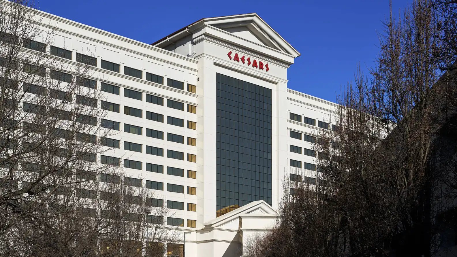 Caesars hotel and casino building exterior with white neoclassical architecture and red signage against a blue sky