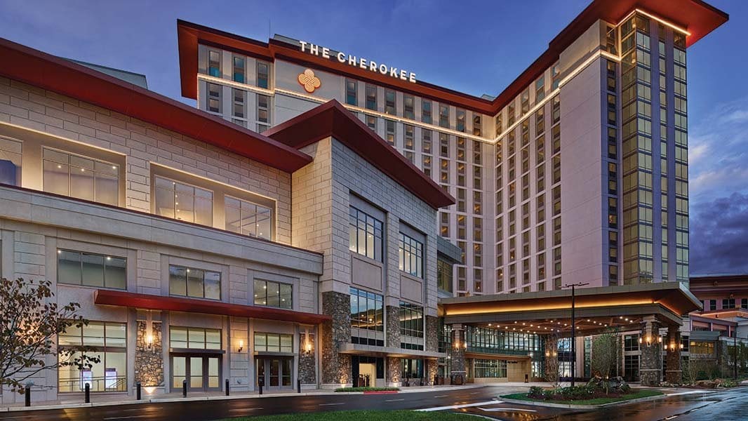 The Cherokee Hotel exterior at dusk featuring modern architecture with stone facade, red accents, and illuminated entrance canopy