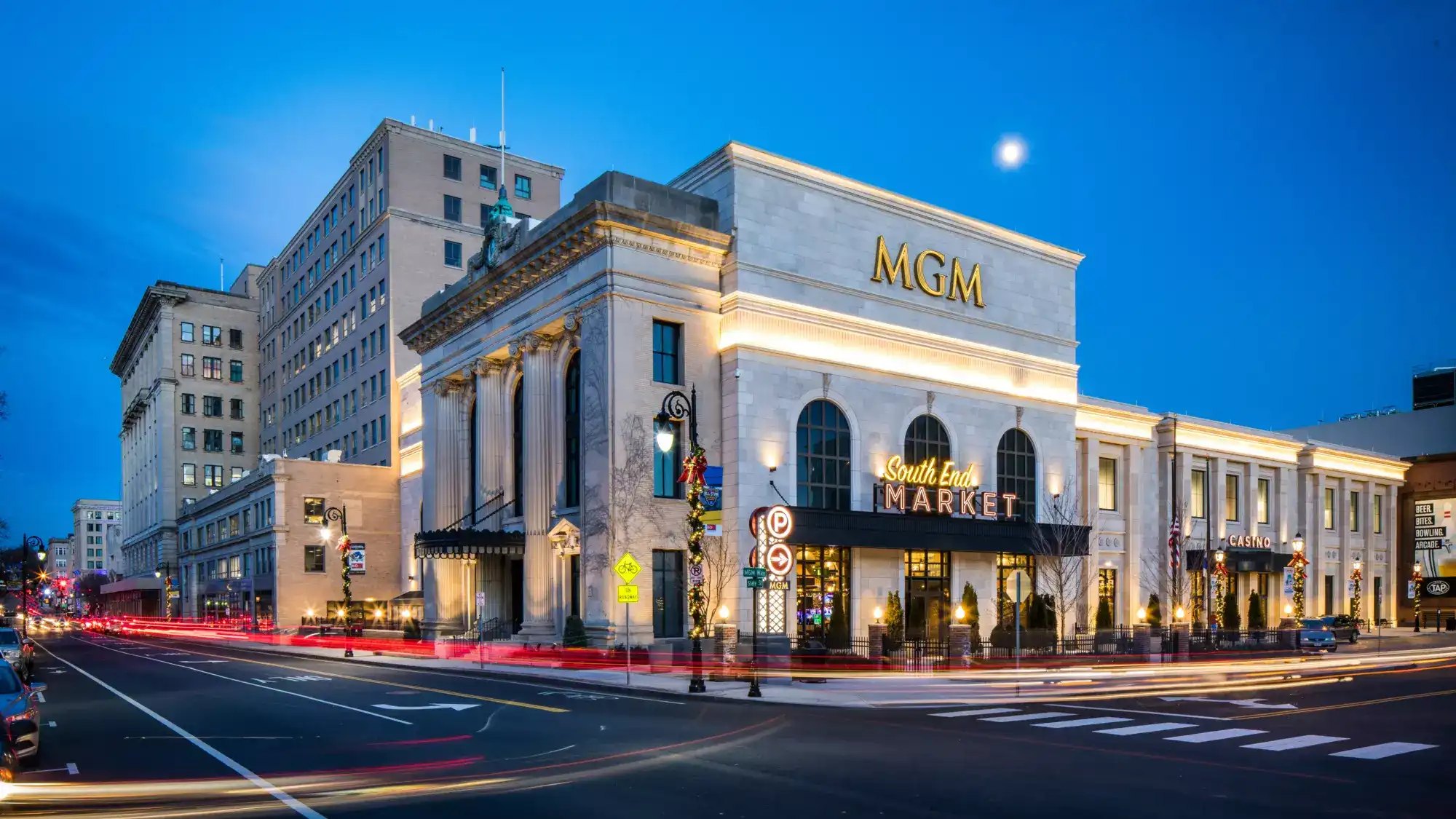 MGM Springfield casino and South End Market building illuminated at night with light trails from passing cars on the street